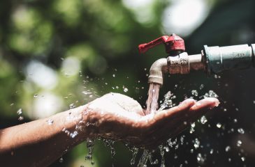 Water concept in everyday life. Hands supporting the water flowing from the faucet. water splashing from the tap